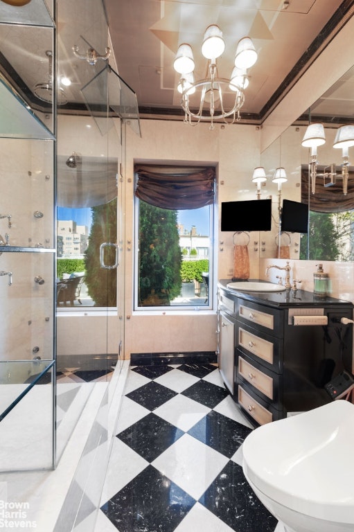 bathroom with vanity, a notable chandelier, and a shower with door