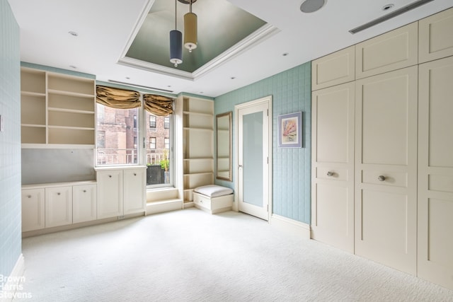 unfurnished bedroom featuring a closet, ornamental molding, light colored carpet, and a raised ceiling