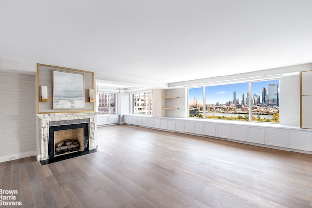 unfurnished living room featuring a fireplace with flush hearth, a view of city, and wood finished floors