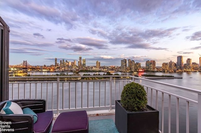 balcony at dusk featuring a water view