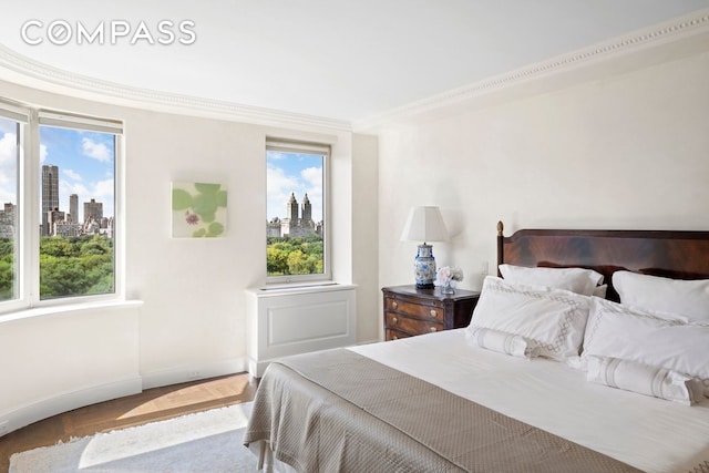 bedroom featuring wood finished floors, multiple windows, a view of city, and crown molding