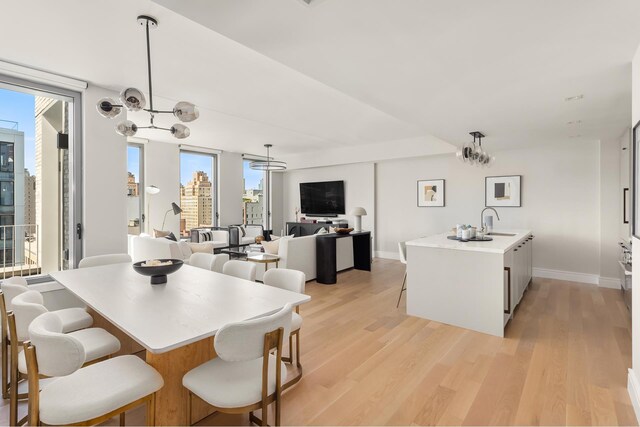 dining area with light hardwood / wood-style floors, sink, and a notable chandelier