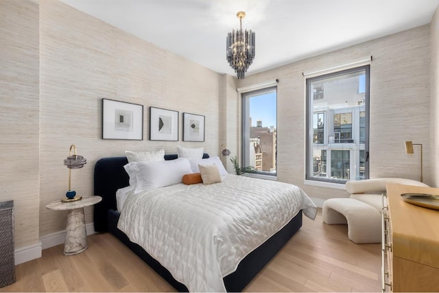 bedroom with light hardwood / wood-style floors and a notable chandelier