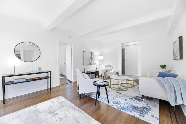 living area featuring dark wood-type flooring, beamed ceiling, and baseboards