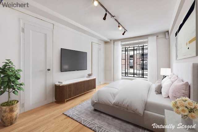 bedroom featuring light wood-type flooring, rail lighting, and access to outside