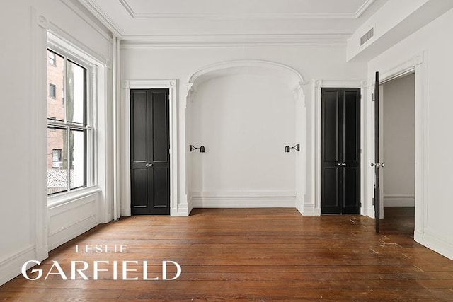 unfurnished room with a wealth of natural light, wood-type flooring, visible vents, and crown molding