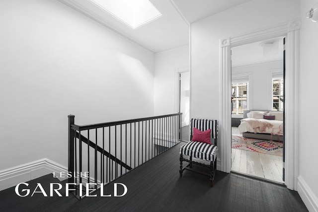 interior space featuring a skylight, wood finished floors, and an upstairs landing