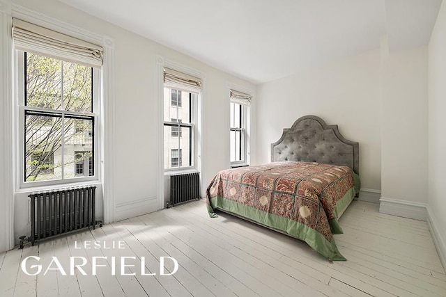 bedroom with radiator, wood-type flooring, and multiple windows