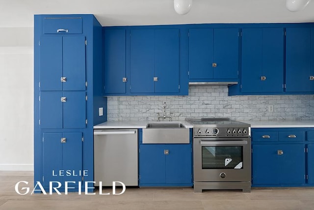 kitchen with light wood-style flooring, appliances with stainless steel finishes, light countertops, and backsplash