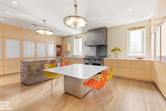 kitchen featuring range with two ovens, a large island, modern cabinets, wall chimney range hood, and pendant lighting