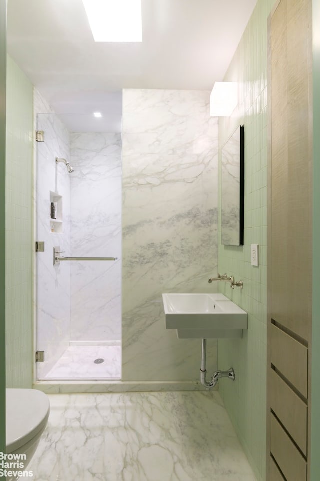 bathroom featuring marble finish floor, toilet, a stall shower, and a sink