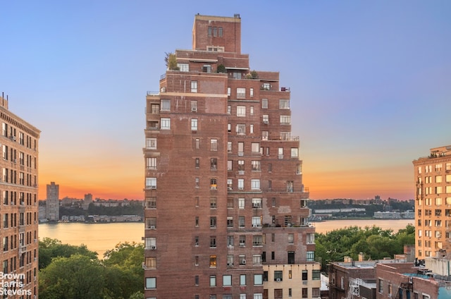 property at dusk with a city view and a water view