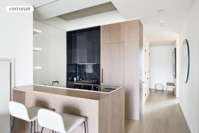 kitchen with a breakfast bar area, visible vents, stainless steel gas stovetop, light wood-style flooring, and modern cabinets