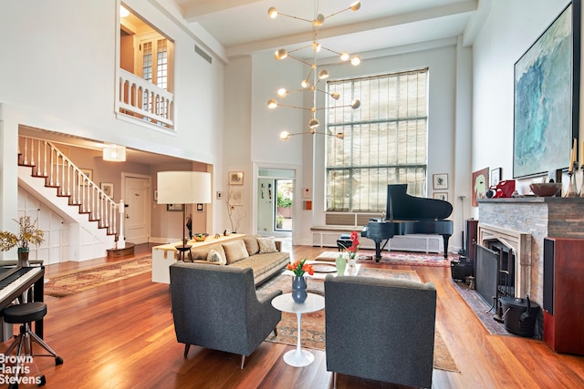 living area featuring beam ceiling, stairway, wood finished floors, and visible vents