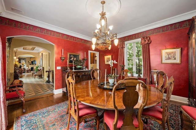 dining space with arched walkways, a chandelier, wood finished floors, baseboards, and ornamental molding