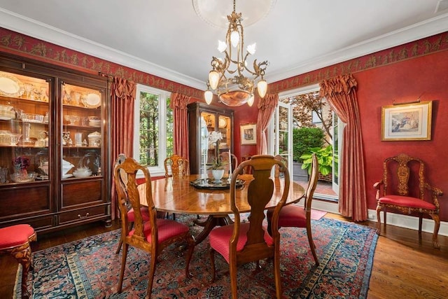 dining room featuring a notable chandelier, ornamental molding, and wood finished floors