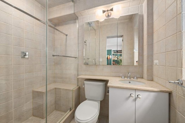 bathroom featuring vanity, toilet, an enclosed shower, and tile walls