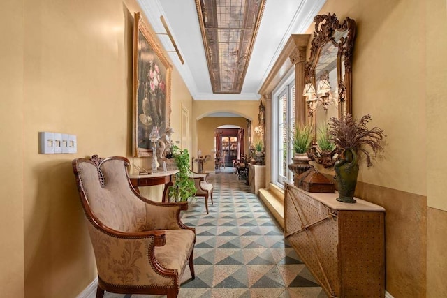 hallway with ornamental molding, arched walkways, and baseboards