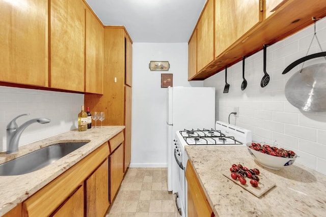 kitchen with tasteful backsplash, light stone countertops, sink, and white gas range