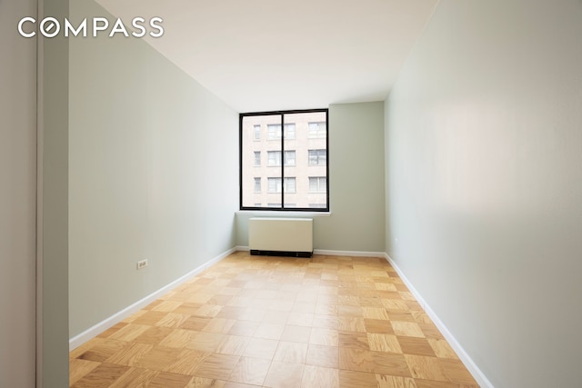 unfurnished room with baseboards and radiator