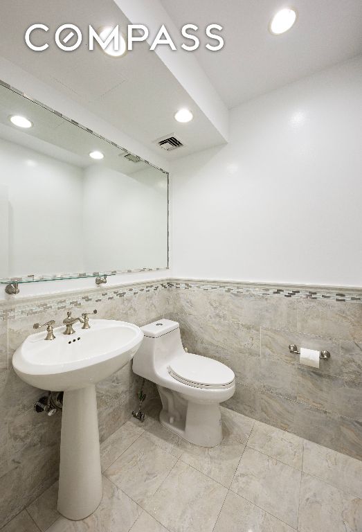 bathroom with recessed lighting, a wainscoted wall, visible vents, and toilet