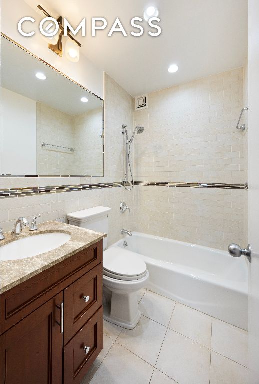 bathroom with decorative backsplash, toilet, tile patterned floors, shower / washtub combination, and tile walls