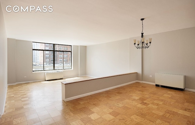 unfurnished room with light parquet flooring, radiator heating unit, and a notable chandelier