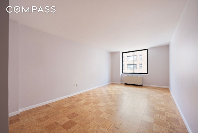 empty room featuring radiator heating unit and baseboards