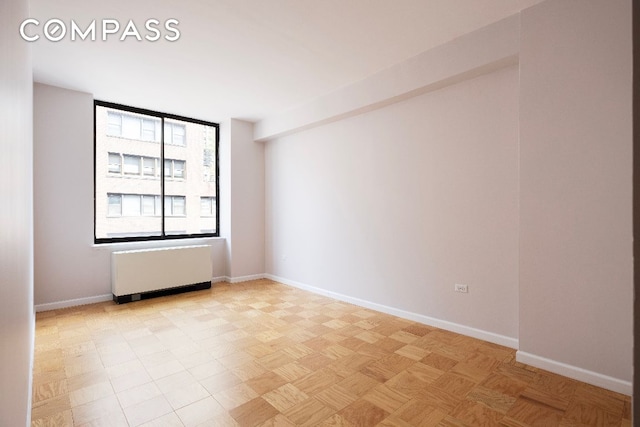 empty room featuring radiator heating unit and baseboards