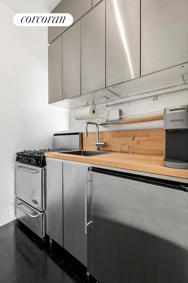 kitchen featuring gray cabinets, a sink, and stainless steel gas range oven