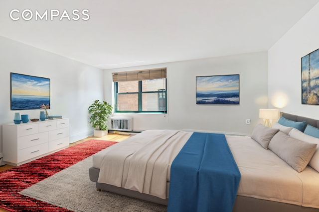 bedroom featuring radiator heating unit, wood finished floors, and baseboards