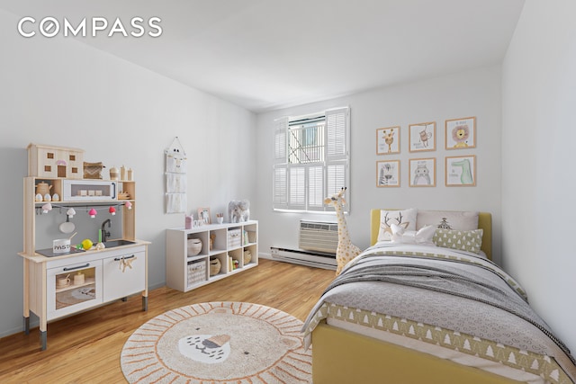 bedroom with baseboard heating, an AC wall unit, and wood finished floors