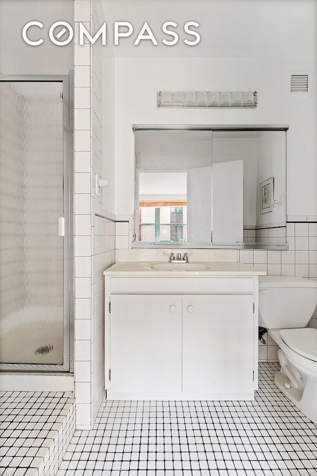 bathroom with vanity, visible vents, a stall shower, tile walls, and toilet