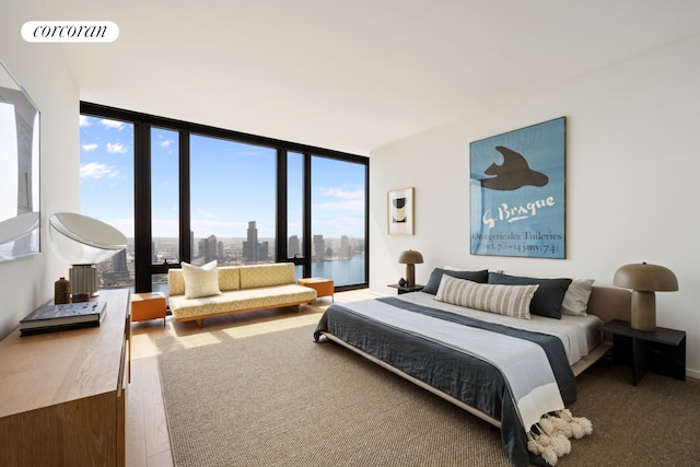 bedroom featuring a view of city, visible vents, a wall of windows, and wood finished floors