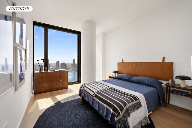 bedroom with a wall of windows and light wood-type flooring