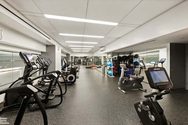 exercise room featuring a paneled ceiling and a wall mounted air conditioner