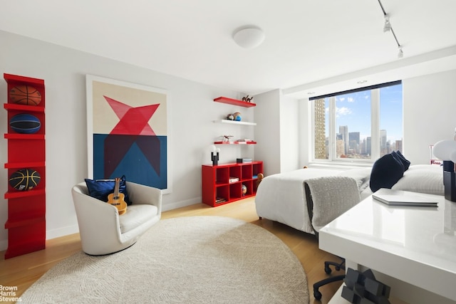 bedroom with rail lighting and hardwood / wood-style floors