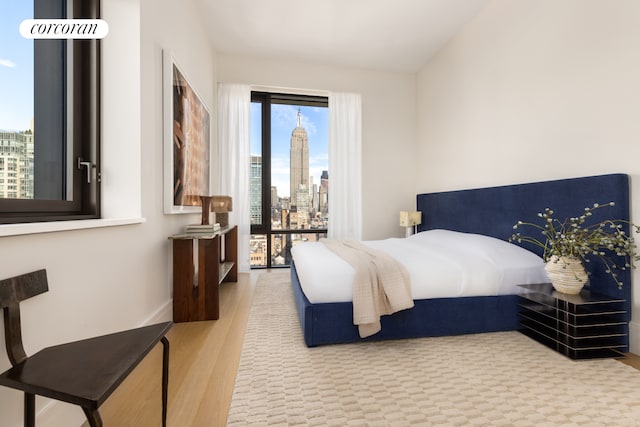 bedroom with a view of city, baseboards, and wood finished floors