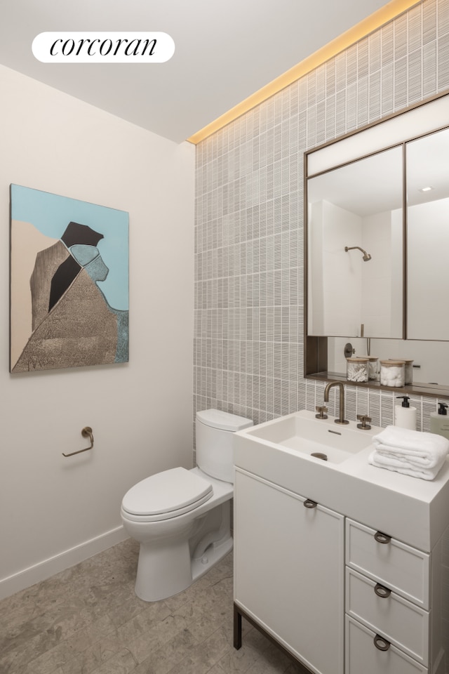 bathroom featuring vanity, toilet, and tile walls