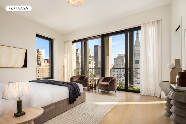 bedroom with access to outside, wood finished floors, visible vents, and a city view