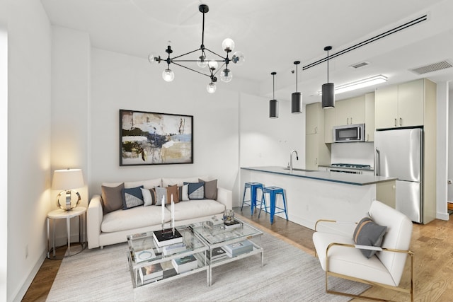 living room with sink, light hardwood / wood-style flooring, and a chandelier