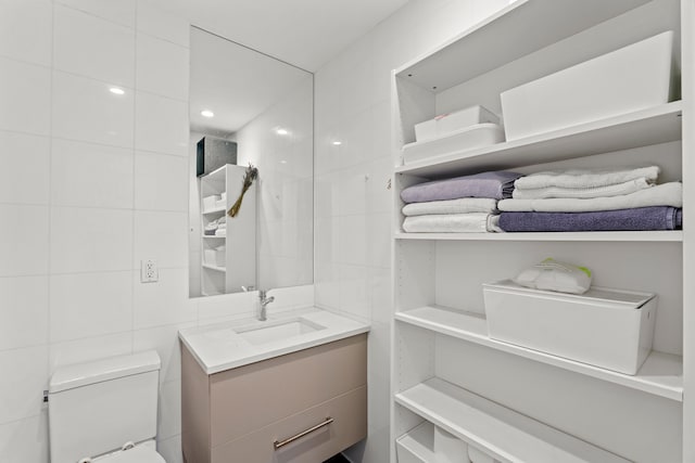 bathroom featuring tile walls, vanity, and toilet