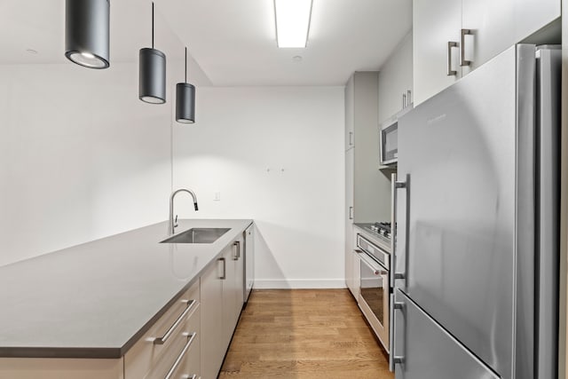 kitchen with a sink, light wood-style floors, stainless steel appliances, a peninsula, and modern cabinets