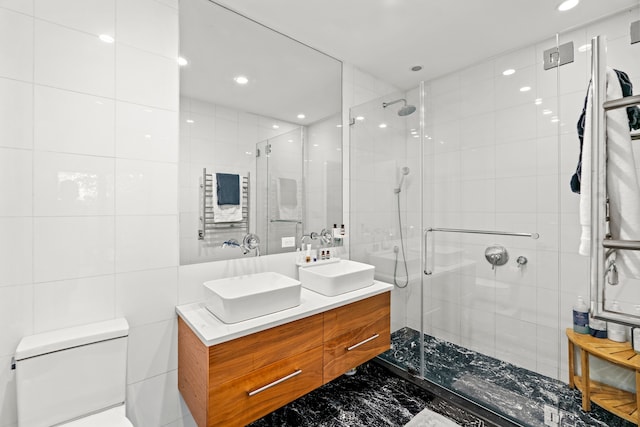 full bath with double vanity, a sink, marble finish floor, and a stall shower