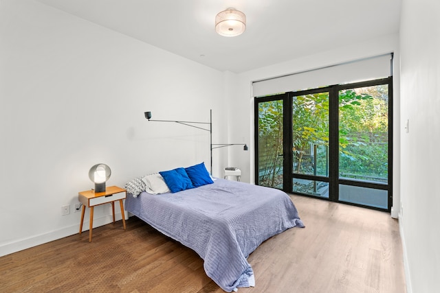 bedroom with baseboards, access to outside, and wood finished floors