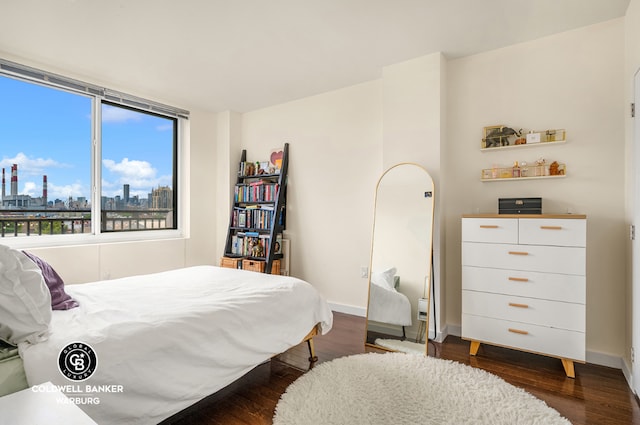 bedroom featuring dark wood-style flooring, a city view, and baseboards