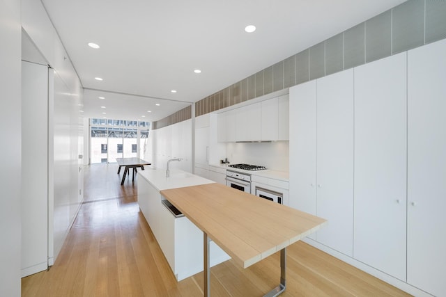 kitchen featuring light wood-style floors, modern cabinets, white cabinets, and white oven