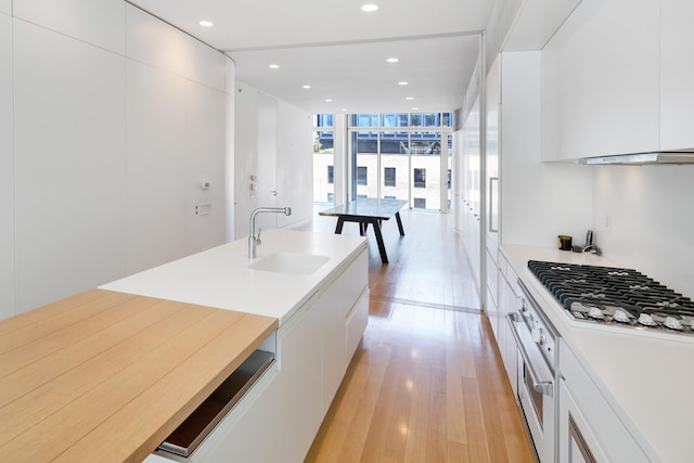 kitchen featuring modern cabinets, expansive windows, light wood-style floors, gas stovetop, and a sink