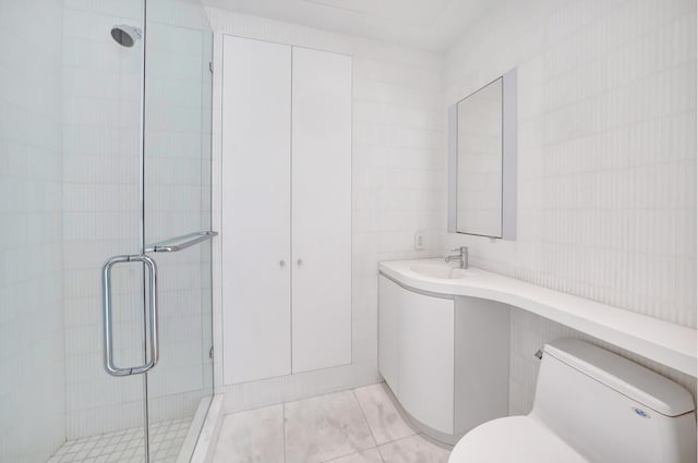 bathroom with tile walls, toilet, a shower stall, vanity, and tile patterned flooring