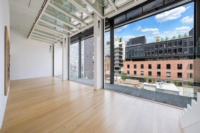 empty room featuring a view of city, expansive windows, and wood finished floors